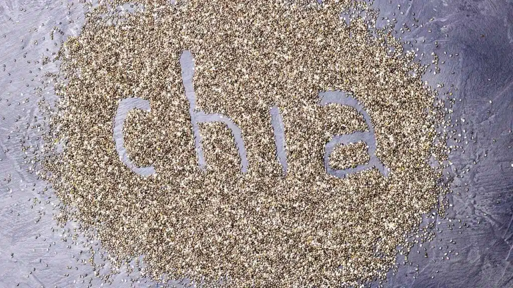 dark Chia seeds with Chia inscription on a black stone background.