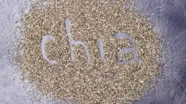 dark Chia seeds with Chia inscription on a black stone background.