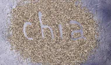 dark Chia seeds with Chia inscription on a black stone background.
