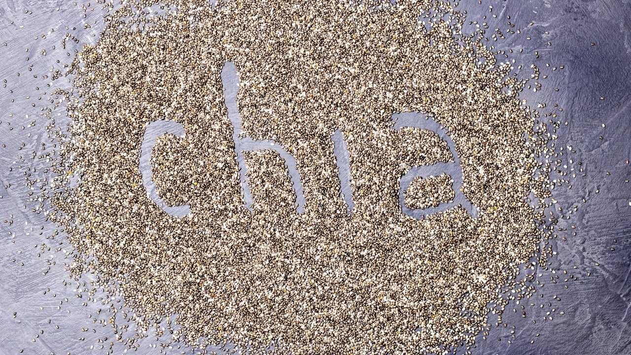 dark Chia seeds with Chia inscription on a black stone background.