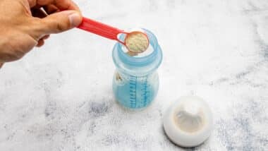 Infant formula being placed with a dispenser in a bottle.