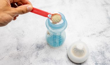 Infant formula being placed with a dispenser in a bottle.