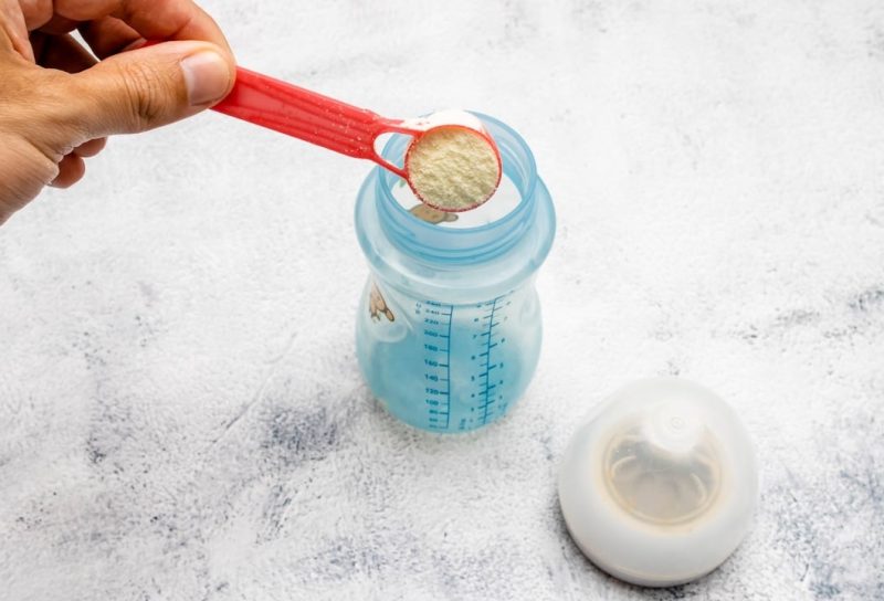 Infant formula being placed with a dispenser in a bottle.