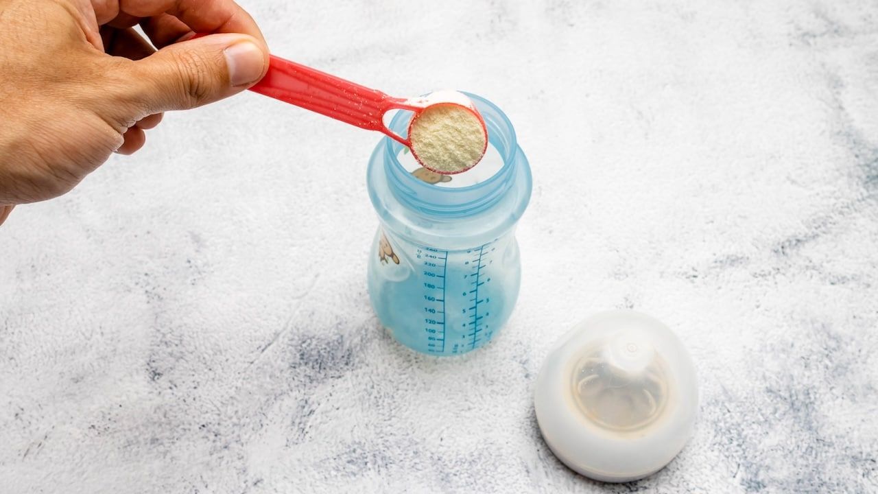 Infant formula being placed with a dispenser in a bottle.