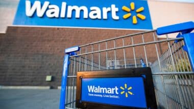 Los Angeles USA A Walmart shopping cart in focus with the store's blue logo and slogan, "Save money. Live better," on a sunny day.