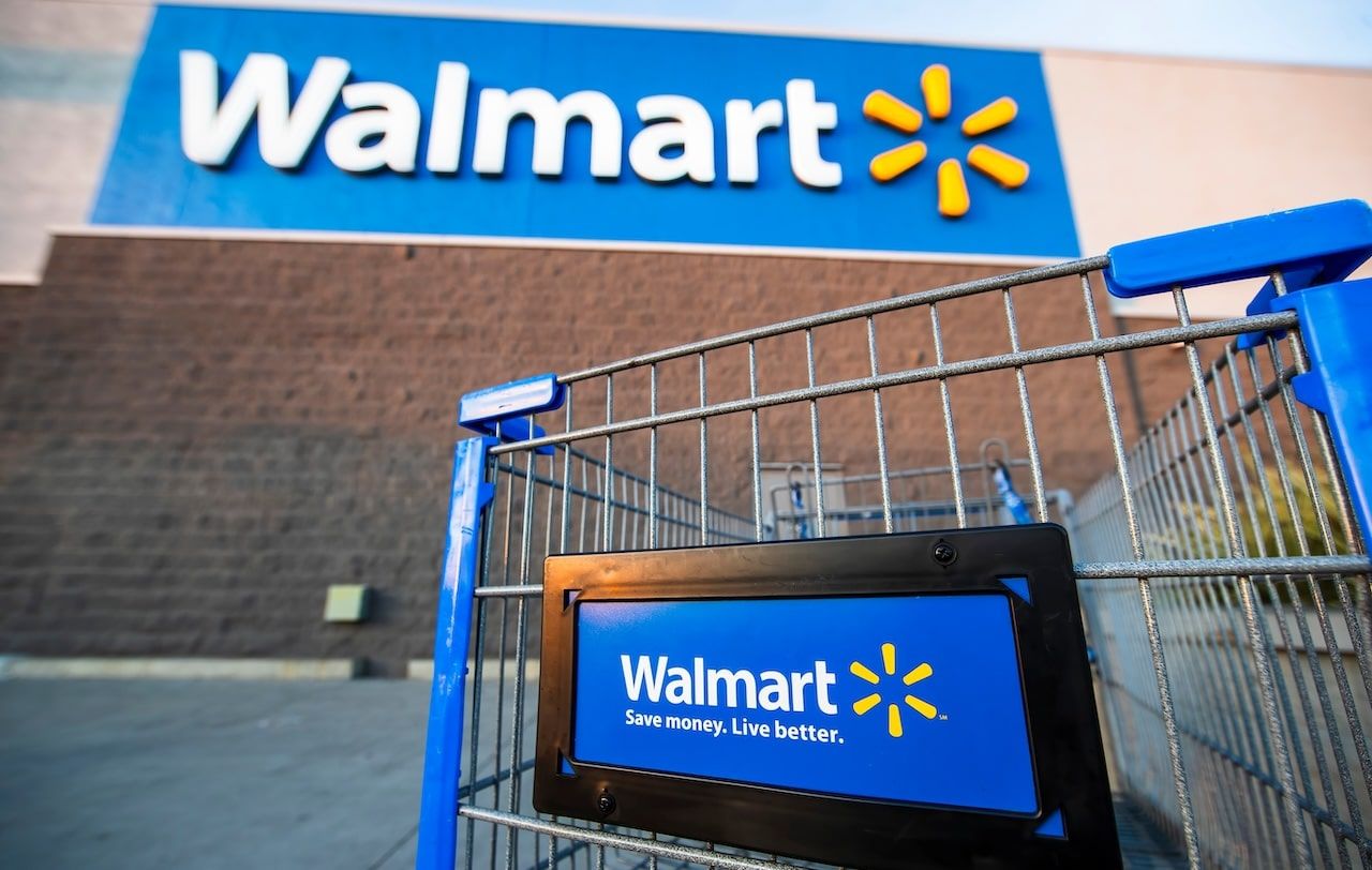 Los Angeles USA A Walmart shopping cart in focus with the store's blue logo and slogan, "Save money. Live better," on a sunny day.