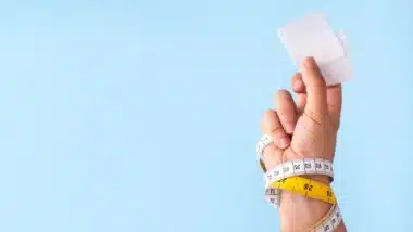 Slim patches with measuring tape and woman hand on blue background