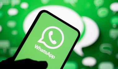 a man holds a smartphone displaying the logo of the WhatsApp instant messaging app