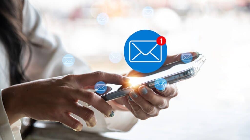 A close-up image of a woman using a smartphone with a glowing new email notification icon.
