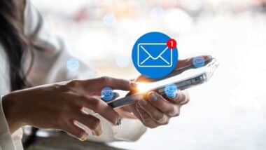 A close-up image of a woman using a smartphone with a glowing new email notification icon.