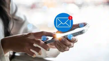 A close-up image of a woman using a smartphone with a glowing new email notification icon.