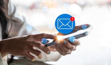 A close-up image of a woman using a smartphone with a glowing new email notification icon.