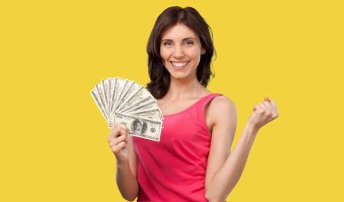 Young happy smart rich woman hold in hand cash money