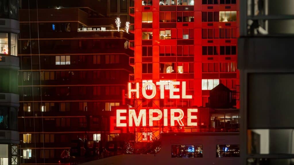 The iconic red neon Hotel Empire sign at night.