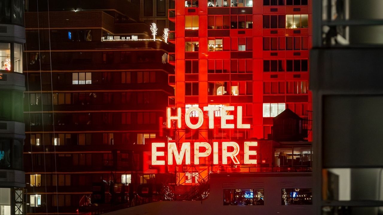 The iconic red neon Hotel Empire sign at night.