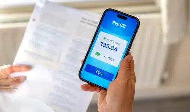 Managing household expenses and utility bills using mobile banking app at home.