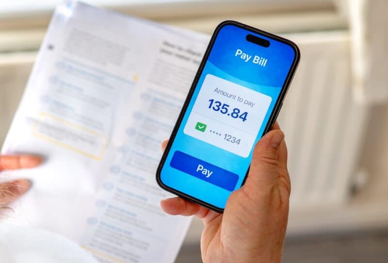 Managing household expenses and utility bills using mobile banking app at home.