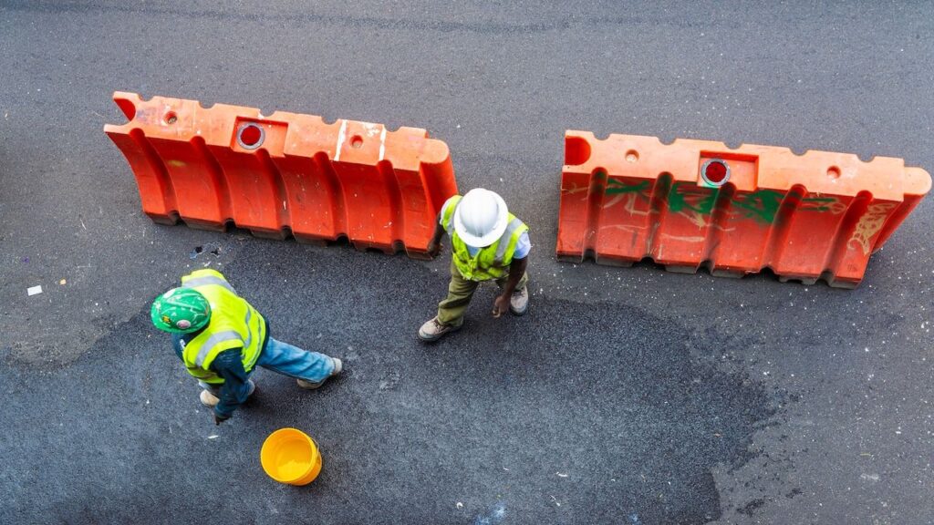 Overview of two construction workers with reflective vest and helmets on a street in New York City, USA