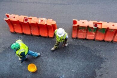 Overview of two construction workers with reflective vest and helmets on a street in New York City, USA