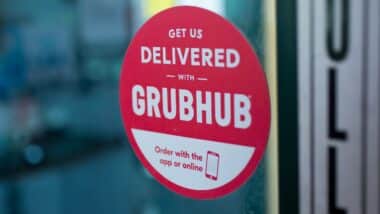 A restaurant front door has an advertisement sticker for Grubhub.