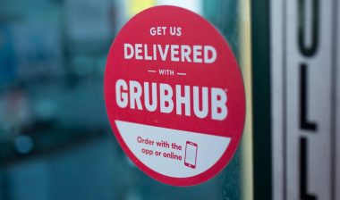 A restaurant front door has an advertisement sticker for Grubhub.