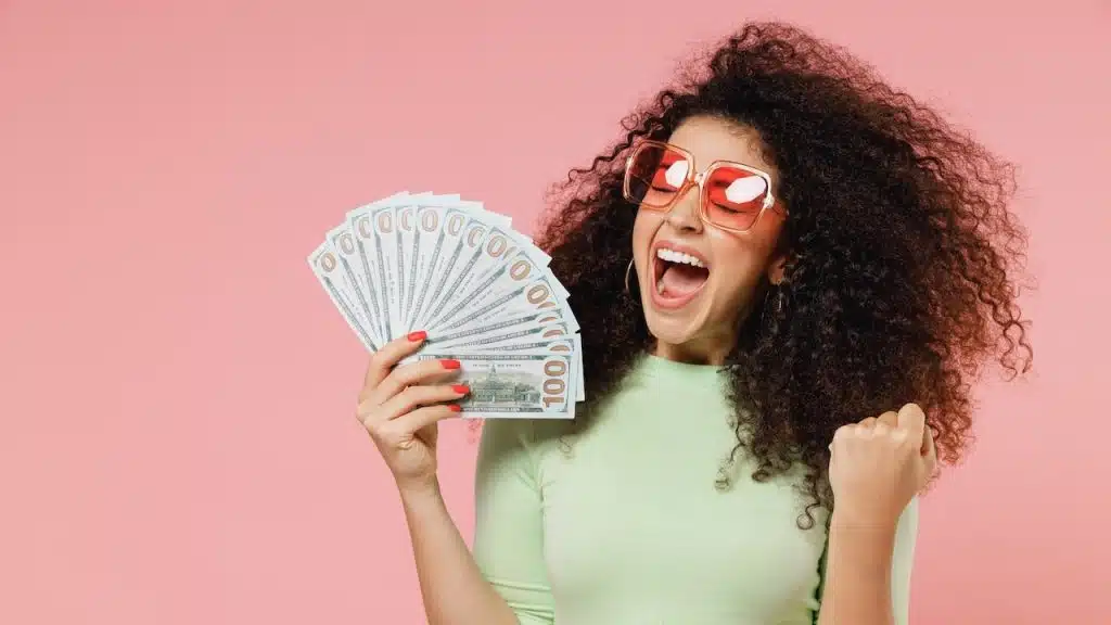 Exultant happy woman 20s hold fan of cash money in dollar banknotes