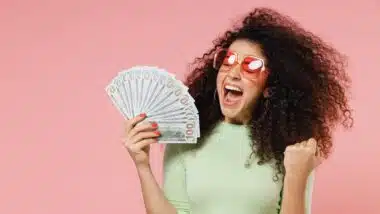 Exultant happy woman 20s hold fan of cash money in dollar banknotes