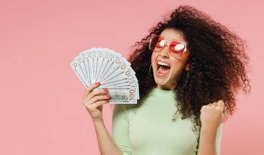 Exultant happy woman 20s hold fan of cash money in dollar banknotes