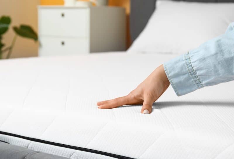 Woman touching soft orthopedic mattress