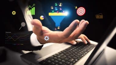 Generating Business leads and customers concept with colorful shapes floating over the hand and laptop in the backdrop.