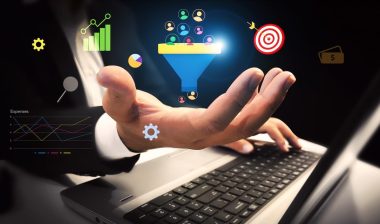 Generating Business leads and customers concept with colorful shapes floating over the hand and laptop in the backdrop.