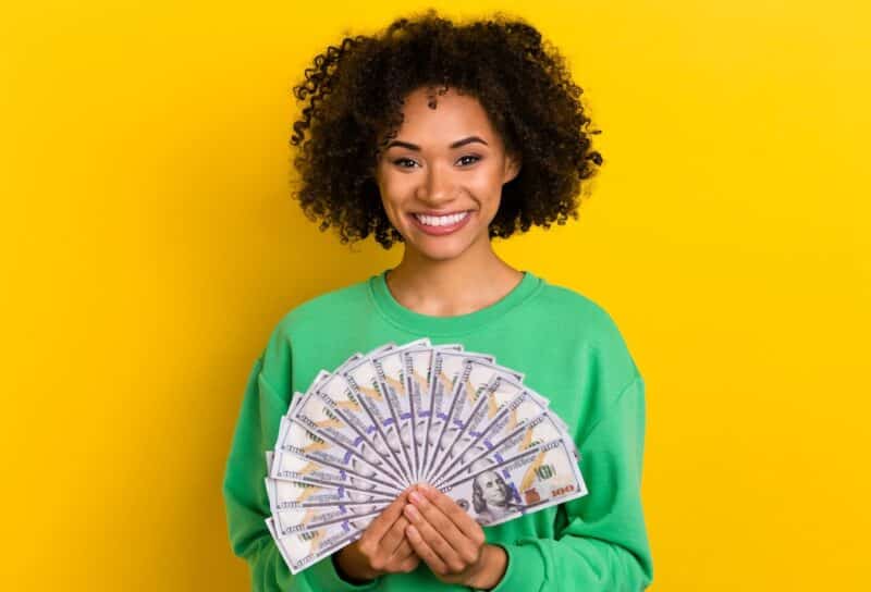 Photo of cheerful pretty lady hold demonstrate usd banknotes