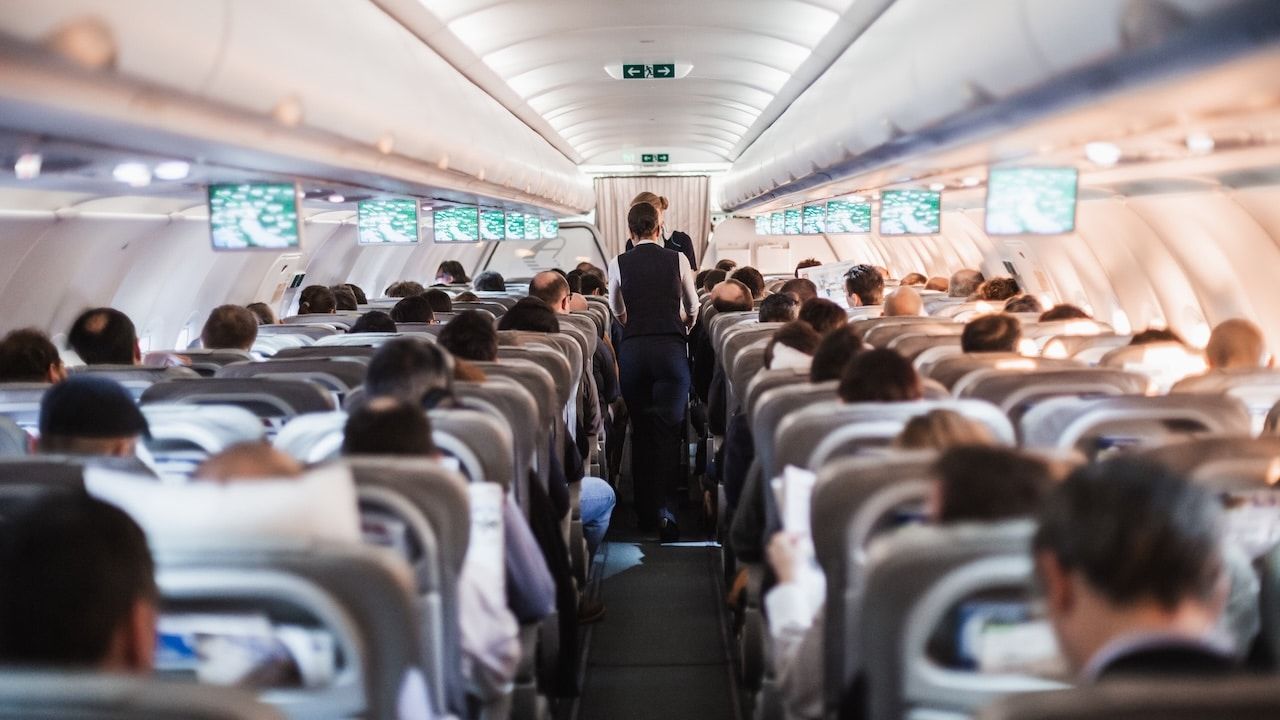 nterior of airplane with passengers on seats and stewardess in uniform