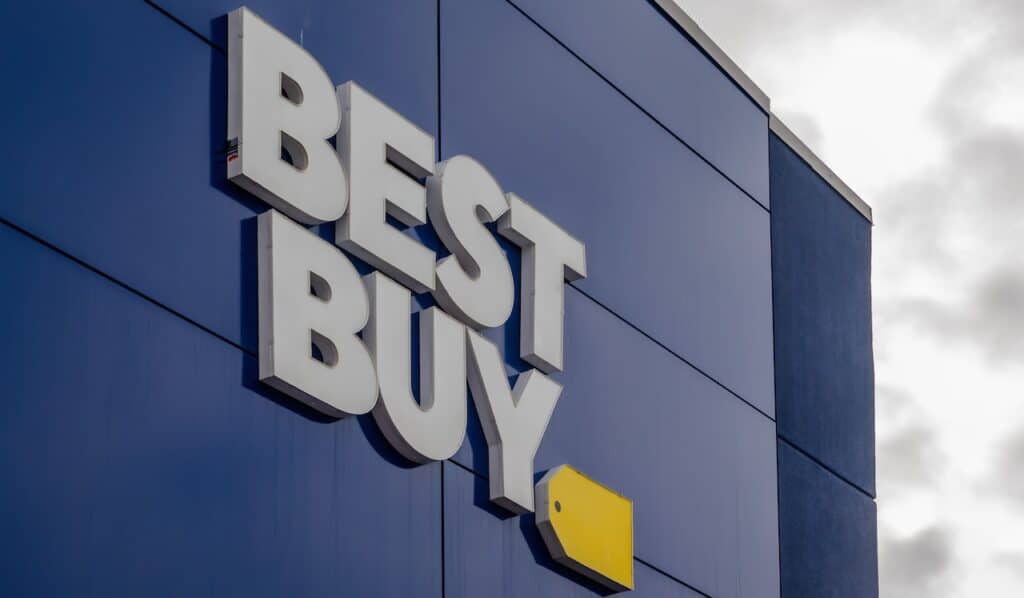 The exterior of a Best Buy store featuring the prominent white "BEST BUY" lettering and yellow tag logo against a dark blue facade.