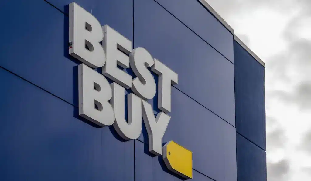 The exterior of a Best Buy store featuring the prominent white "BEST BUY" lettering and yellow tag logo against a dark blue facade.