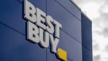 The exterior of a Best Buy store featuring the prominent white "BEST BUY" lettering and yellow tag logo against a dark blue facade.