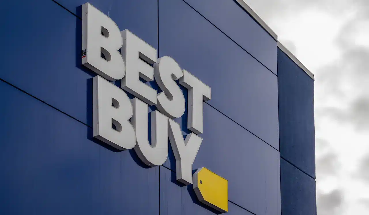 The exterior of a Best Buy store featuring the prominent white "BEST BUY" lettering and yellow tag logo against a dark blue facade.
