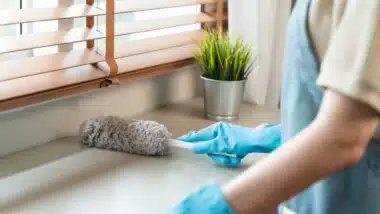 housemaid cleaning furniture surface with sanitizer spray and wiping with wet cloth in living room