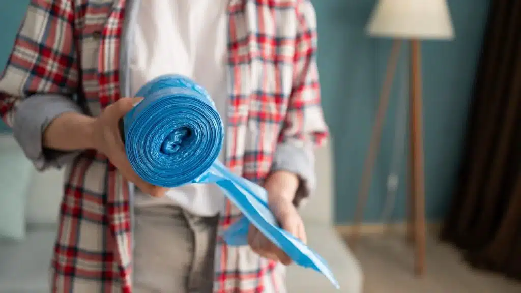 woman hands holding blue roll of plastic garbage bag
