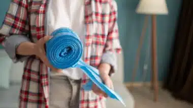 woman hands holding blue roll of plastic garbage bag