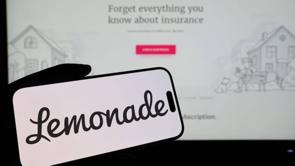Smartphone displaying US insurtech company Lemonade logo in front of companys webpage