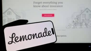 Smartphone displaying US insurtech company Lemonade logo in front of companys webpage