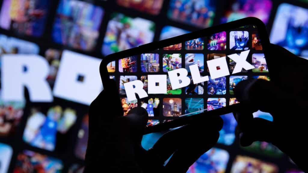 Person holding a smartphone with Roblox game logo