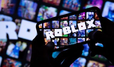 Person holding a smartphone with Roblox game logo