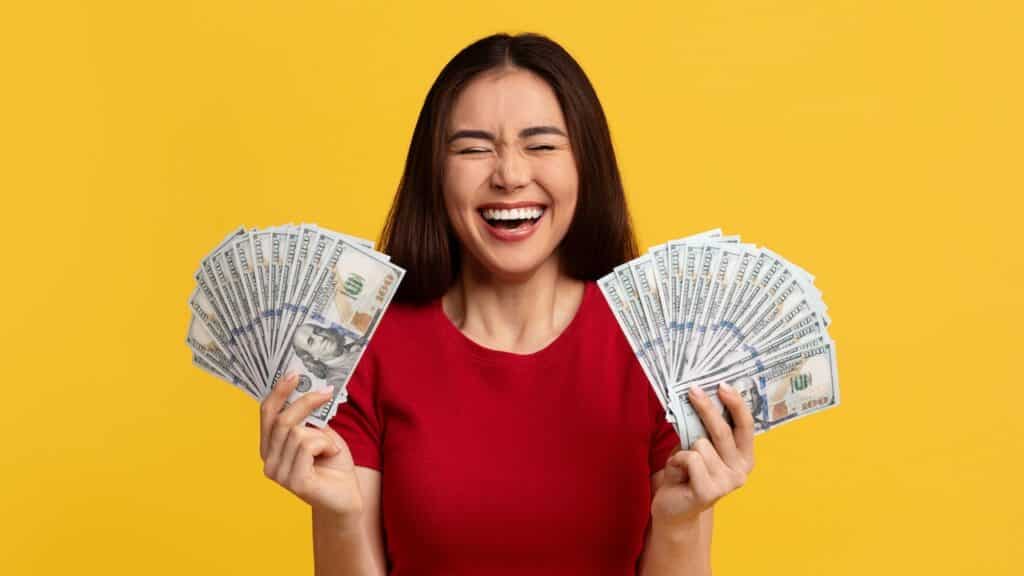 woman with closed eyes holding bunch of money cash dollar banknotes