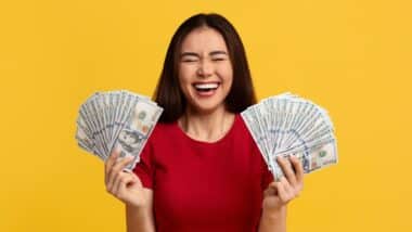woman with closed eyes holding bunch of money cash dollar banknotes