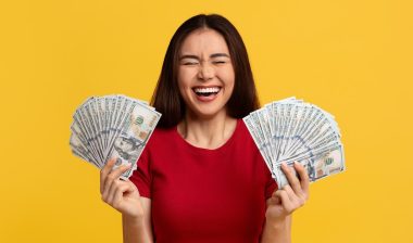 woman with closed eyes holding bunch of money cash dollar banknotes