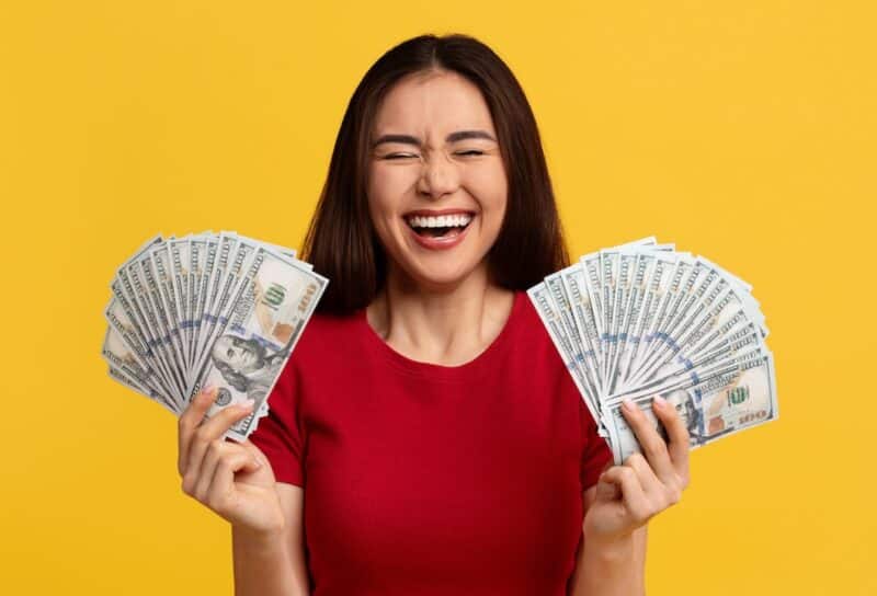 woman with closed eyes holding bunch of money cash dollar banknotes