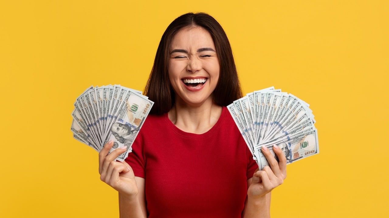 woman with closed eyes holding bunch of money cash dollar banknotes