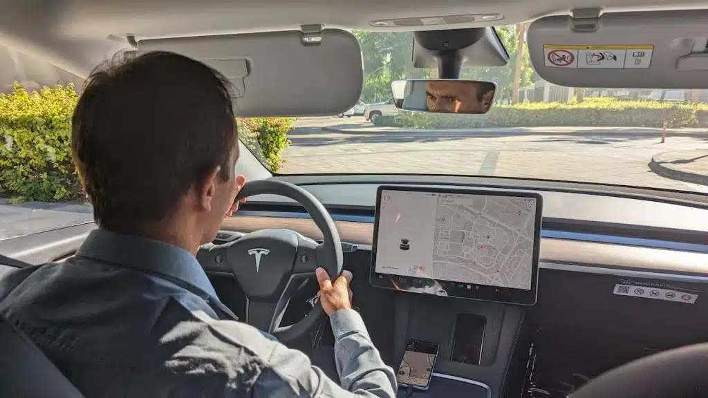 A driver drives a Tesla car on a city road